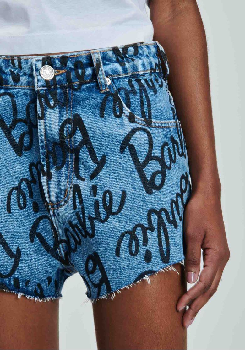Close-frontal-do-short-jeans-azul-estampado-Barbie-com-botao-passantes-no-cos-e-barra-desfiada