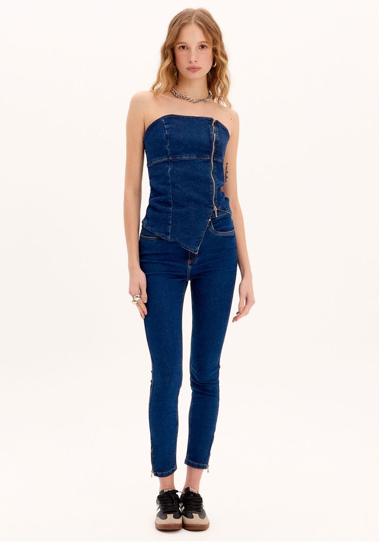 Modelo vestindo calça jeans skinny ankle azul com top sem alças.