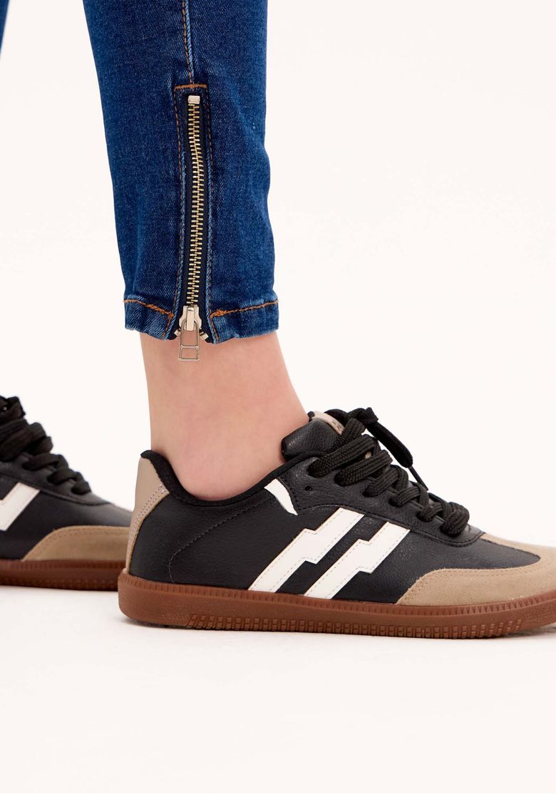 Detalhe do zíper na barra da calça jeans skinny ankle azul.