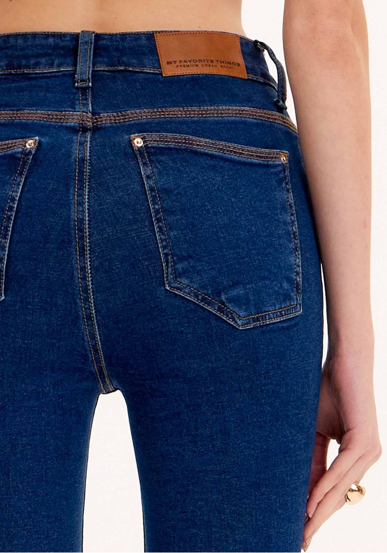 Close-up dos bolsos traseiros da calça jeans skinny ankle azul.