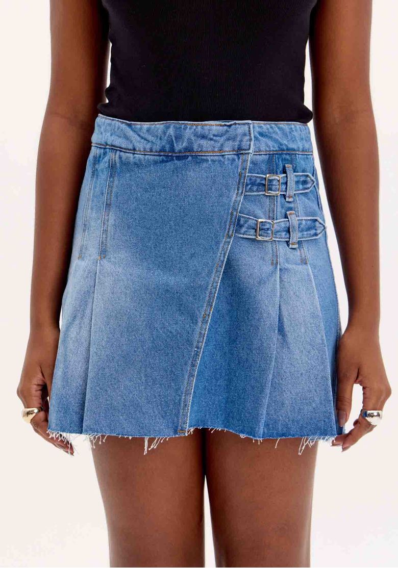 Detalhe das fivelas laterais e pregas da saia curta jeans.