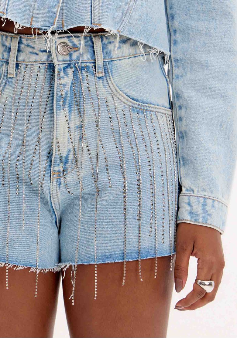Vista traseira do short jeans Grandfather Brilho mostrando bolsos traseiros e barra desfiada; jaqueta jeans combinando em lavagem clara.