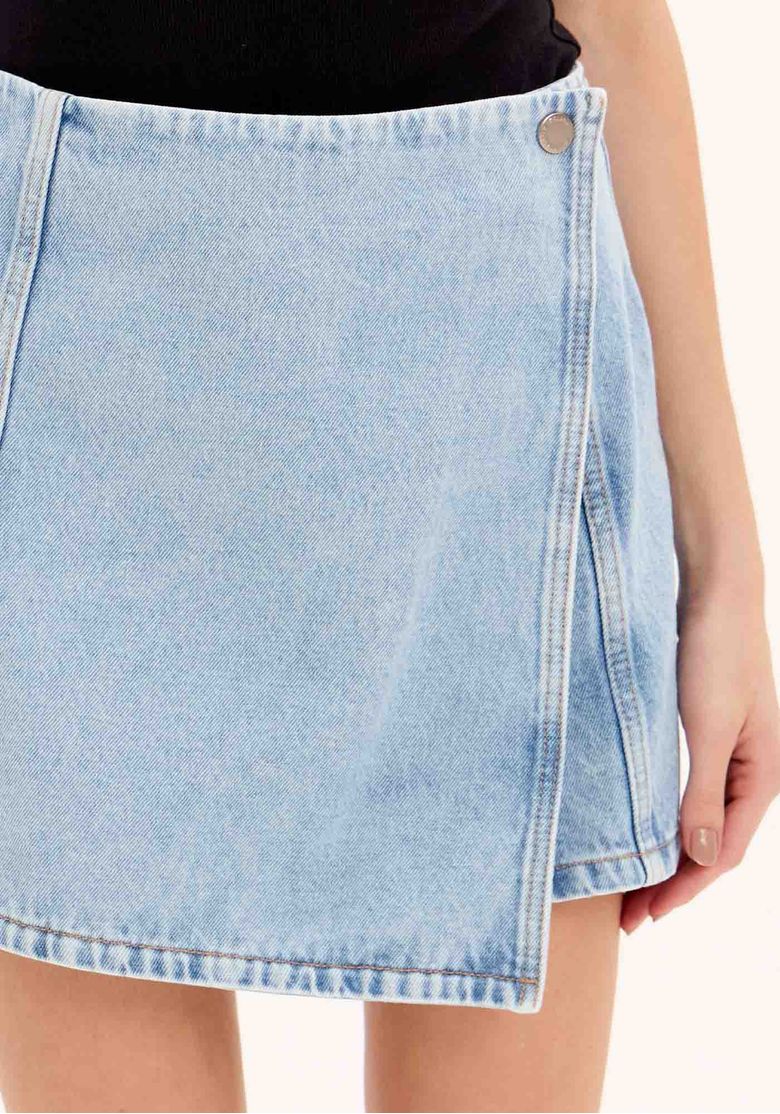 Visualização traseira do short saia jeans de lavagem clara, evidenciando caimento, costura central e barra simples - peça denim 100% algodão.