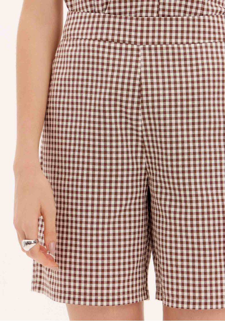 Detalhe da cintura alta e bolsos funcionais da bermuda xadrez.