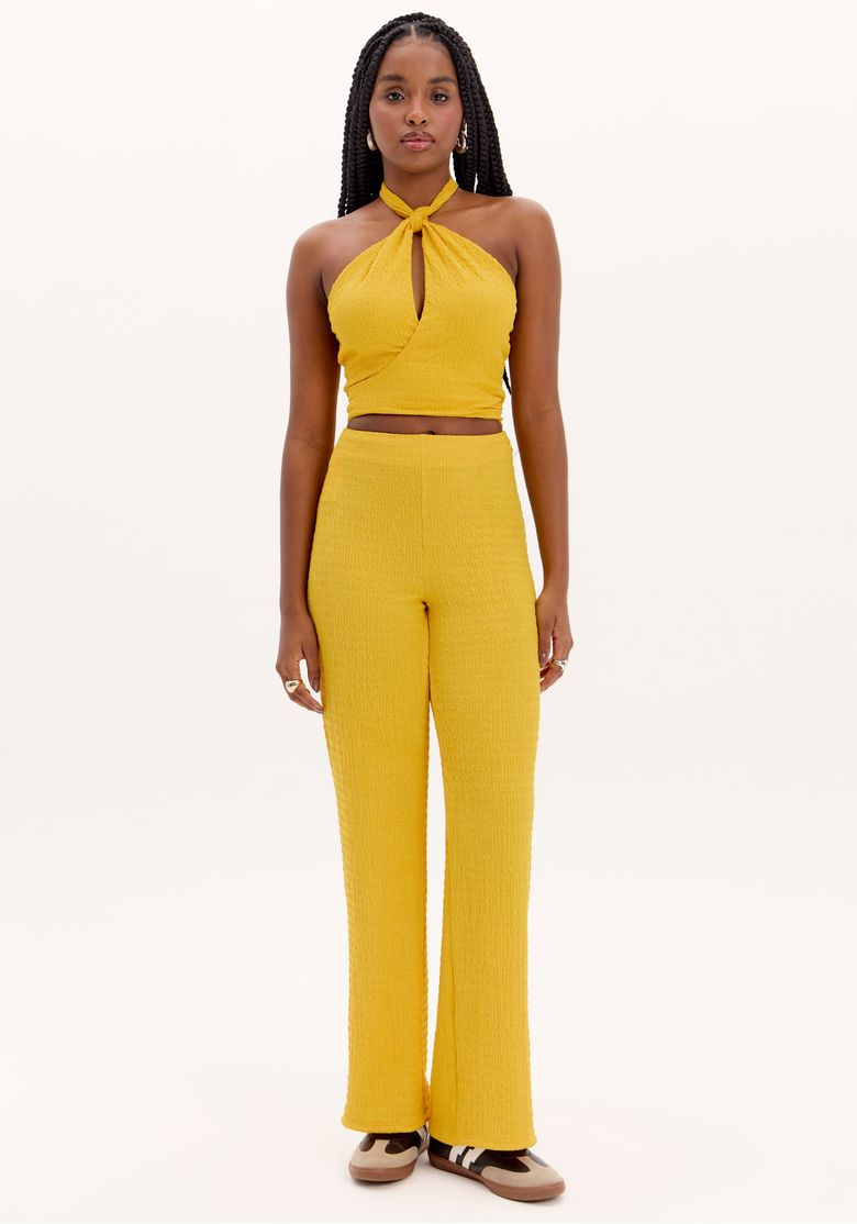 Modelo vestindo calça reta texturizada amarela com cintura alta, vista frontal.