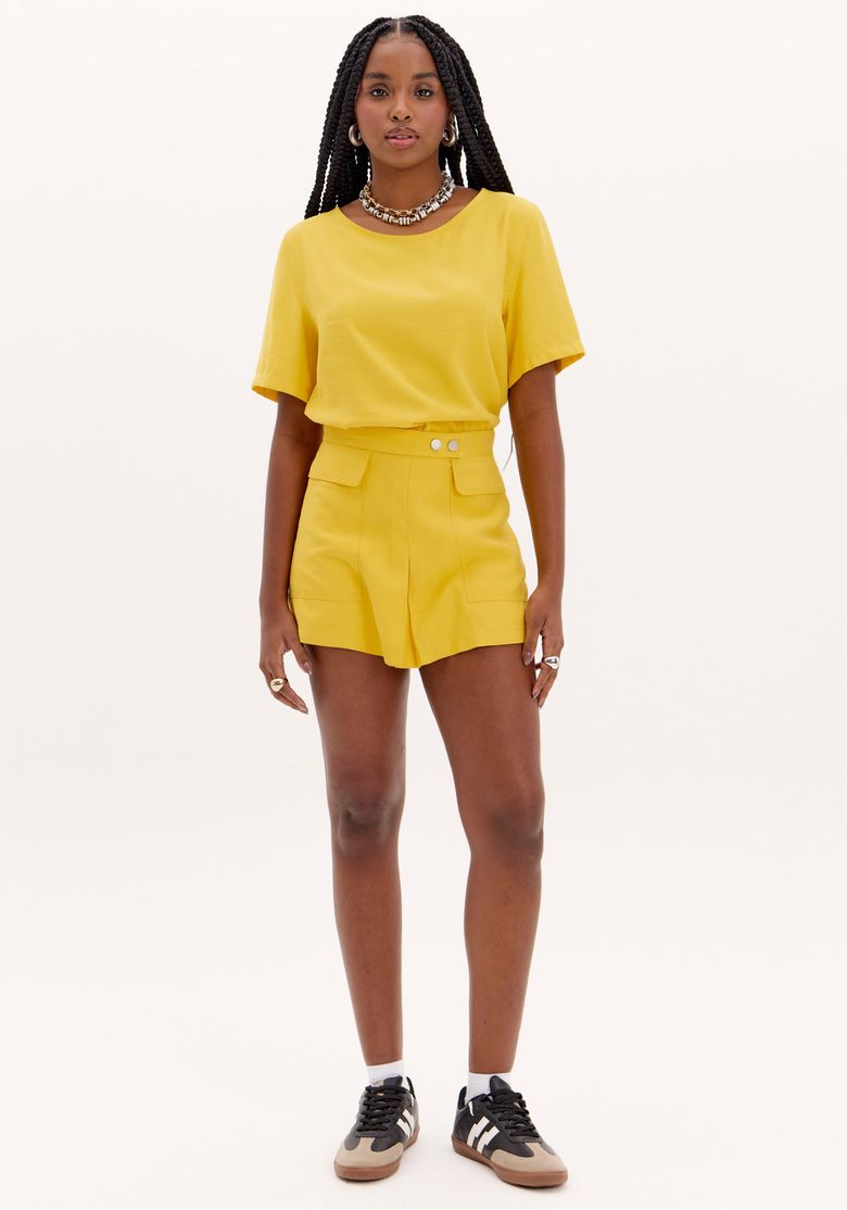 Modelo-vestindo-short-saia-amarelo-com-maxi-bolsos-e-top-combinando-vista-frontal.