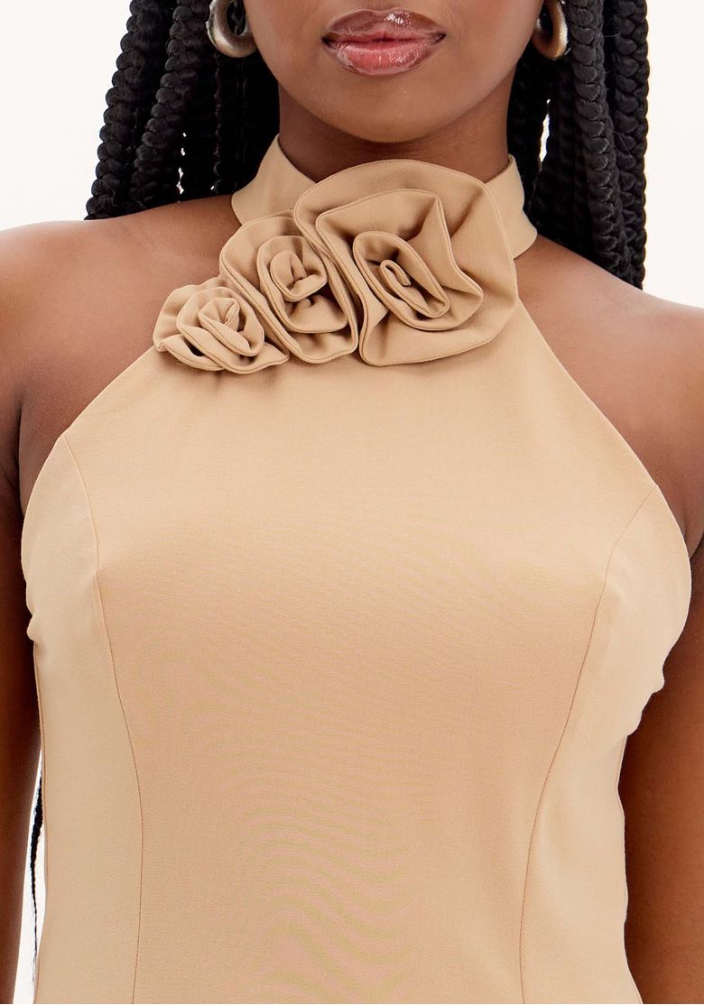 Close no vestido curto bege com gola alta e flores aplicadas no decote, destacando o acabamento sofisticado.
