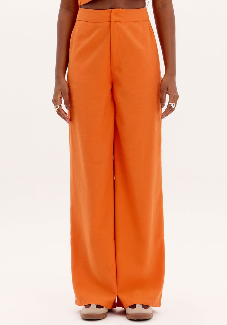 Vista traseira da calça wide leg laranja evidenciando cós alto, costura traseira limpa e perna larga com acabamento reto