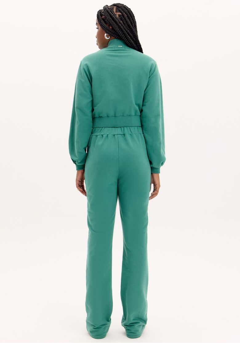 Modelo vestindo a calça boot cut verde com um top cropped, mostrando o visual completo.