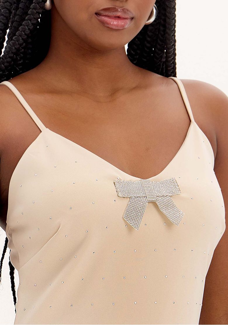 Detalhe do laço decorativo e aplicações de brilho no vestido.
