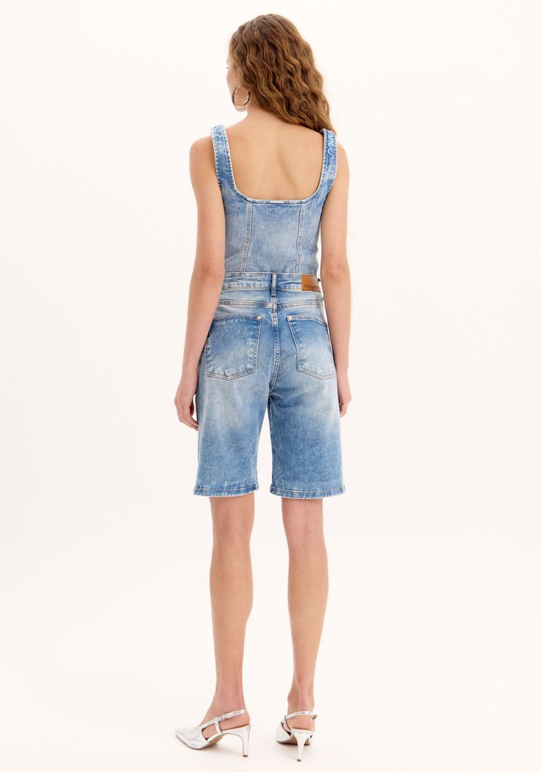 Vista traseira da bermuda jeans alongada em lavagem azul, mostrando bolsos traseiros chapados e caimento reto - bermuda cintura alta