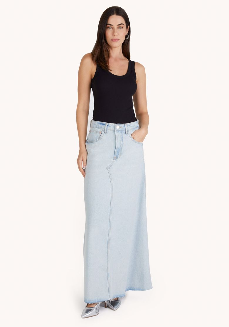 Modelo usando saia jeans azul clara de cintura alta com top preto e sapato prata em vista frontal