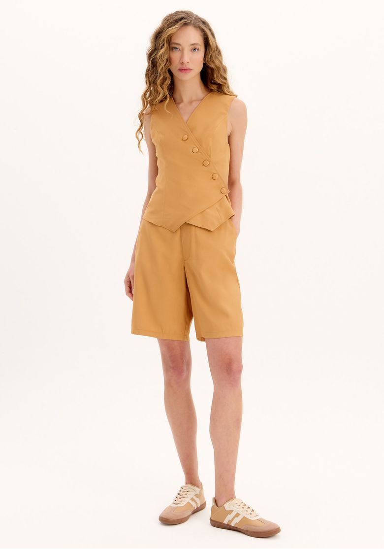 Modelo usando bermuda alfaiataria marrom vista frontal, cintura alta com cinto e bolsos funcionais, look work sofisticado