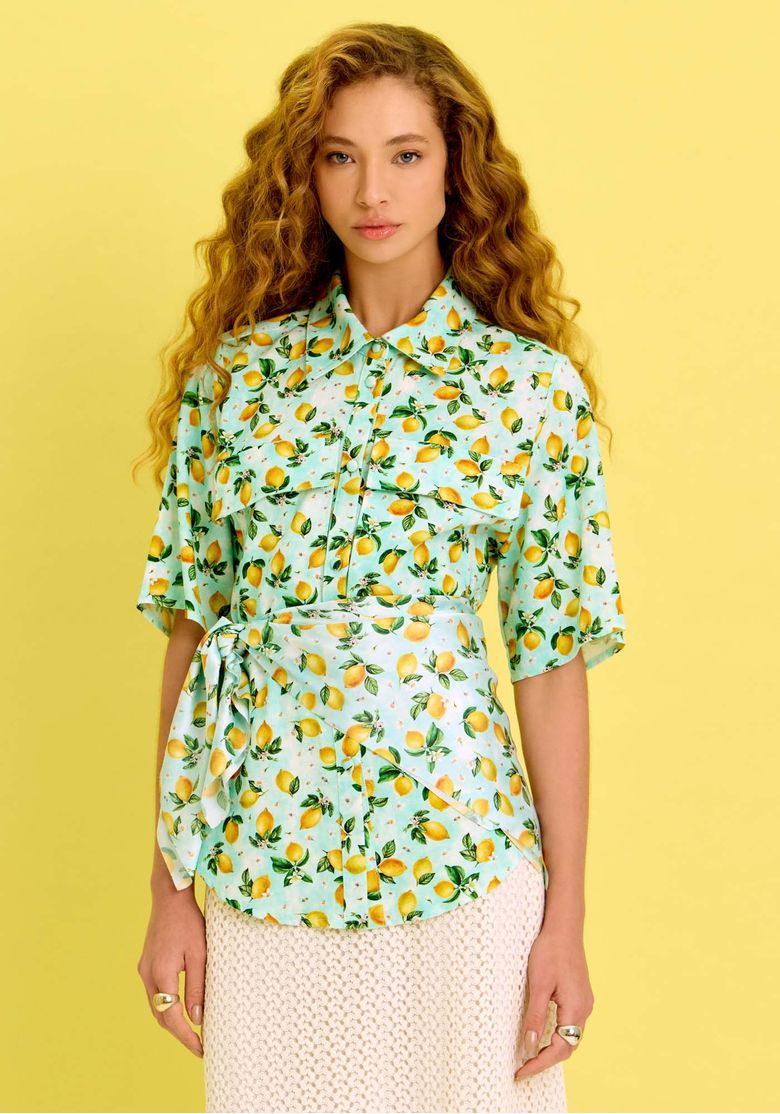 Modelo vestindo camisa alongada estampada com limões sicilianos, com mangas curtas e bolsos frontais.