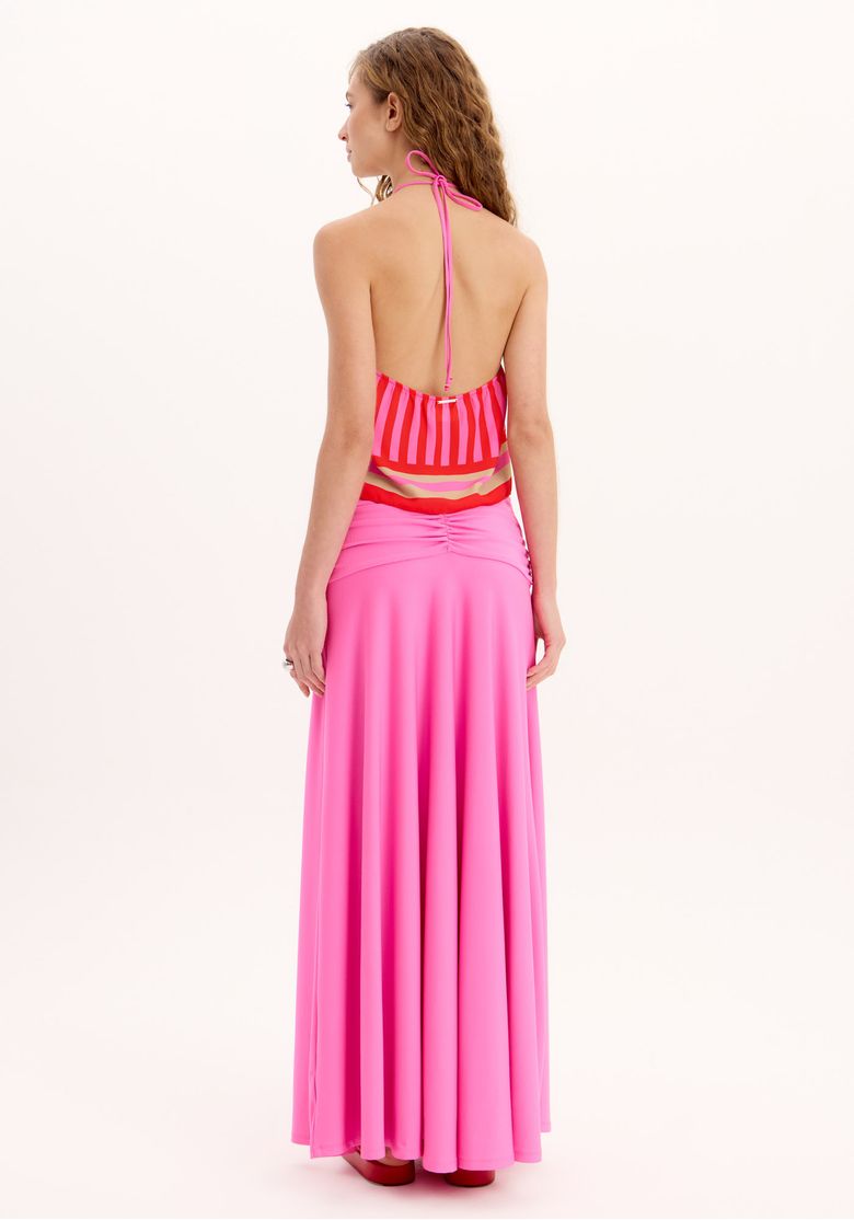 Vista traseira do look mostrando saia midi rosa franzida na cintura média e top halter com costas abertas