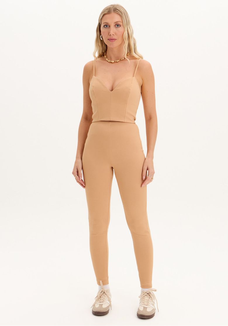 Modelo usando calça legging fusô bege feminina de cintura alta com caimento ajustado e comprimento longo em look casual urbano