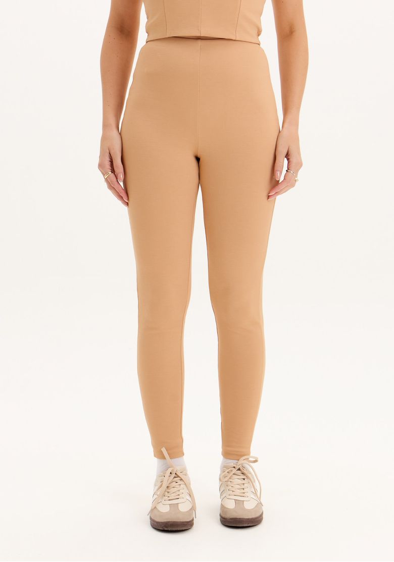 Close frontal da calça legging fusô bege feminina mostrando cintura alta, modelagem legging e barra simples