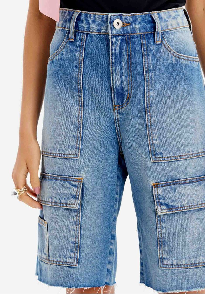 Close frontal da bermuda jeans cargo azul feminina com cintura alta, passantes no cós, botão frontal e bolsos cargo laterais