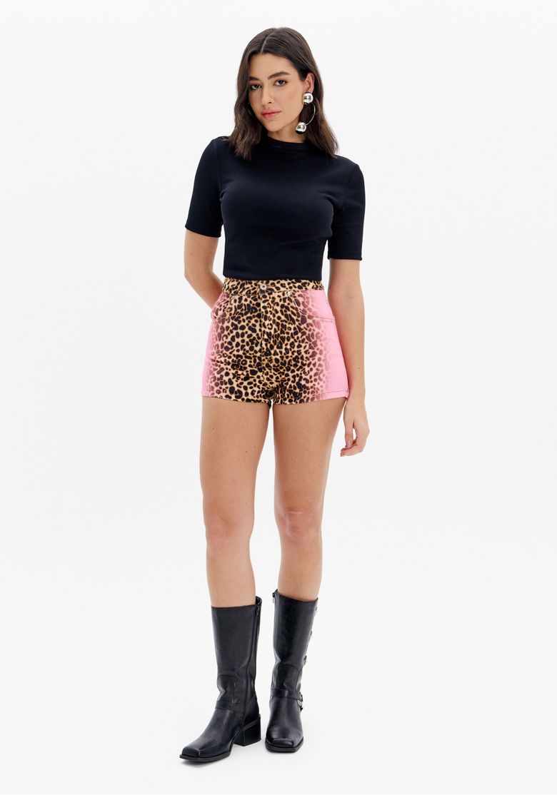 Modelo vestindo short de sarja com estampa animal print e degradê lateral, combinado com top preto e botas.