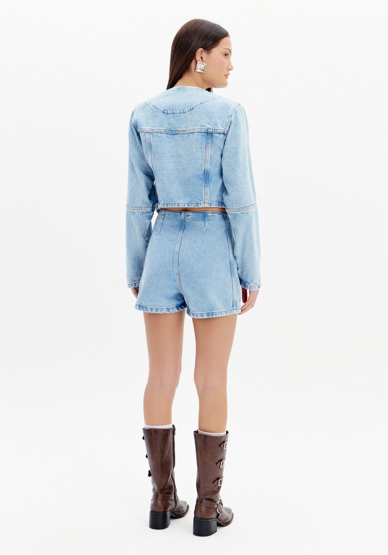 Modelo vestindo short jeans com fivela e top jeans, vista traseira.