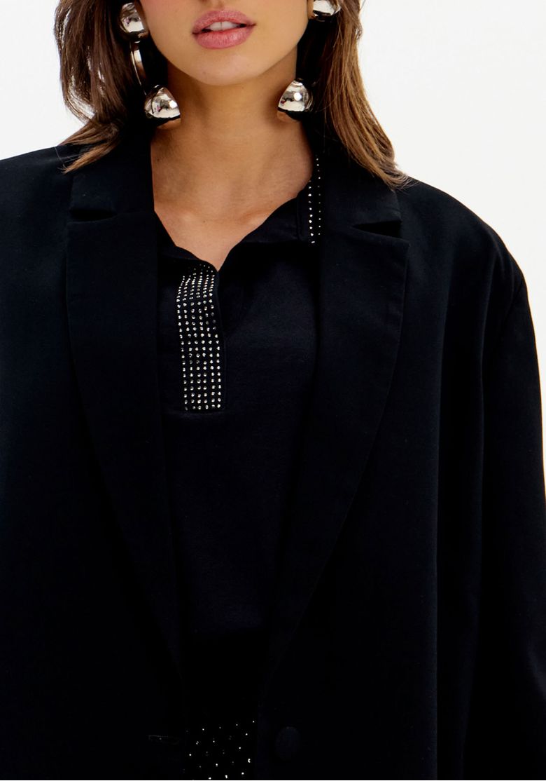 Close superior do blazer de alfaiataria preto feminino com lapela clássica e fechamento frontal por botão