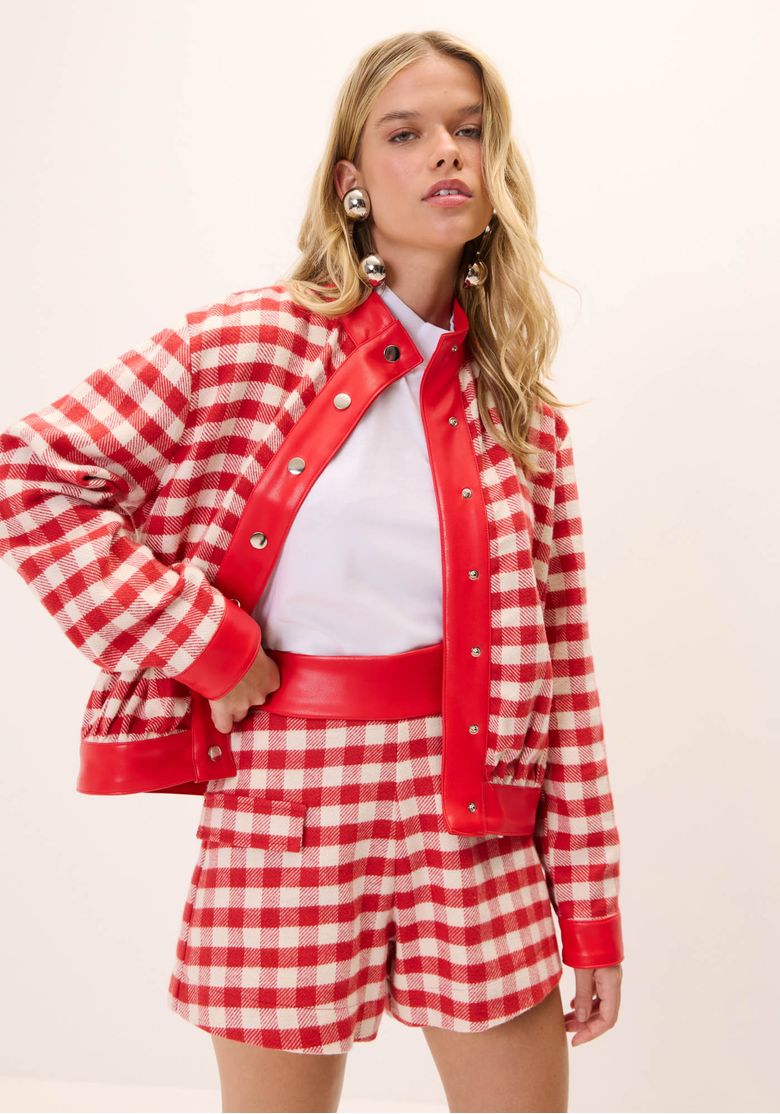 Modelo usando jaqueta xadrez curta vermelha feminina com bolso frontal chapado e shorts xadrez coordenado