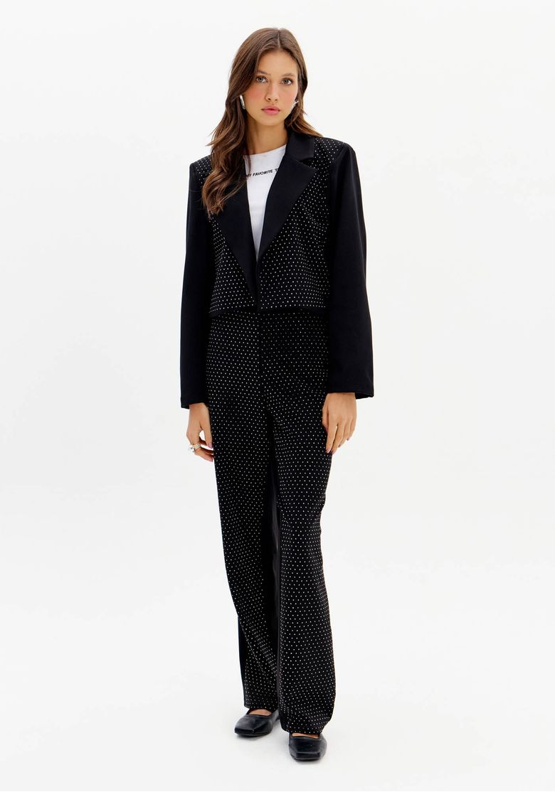 Modelo vestindo calça reta de alfaiataria preta com brilhos, combinada com blazer preto.