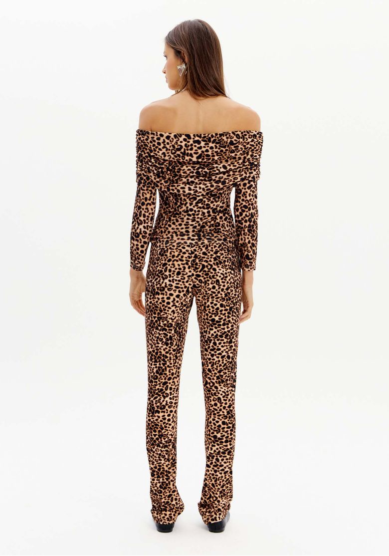 Modelo de costas vestindo conjunto com estampa animal print, incluindo a calça boot cut.