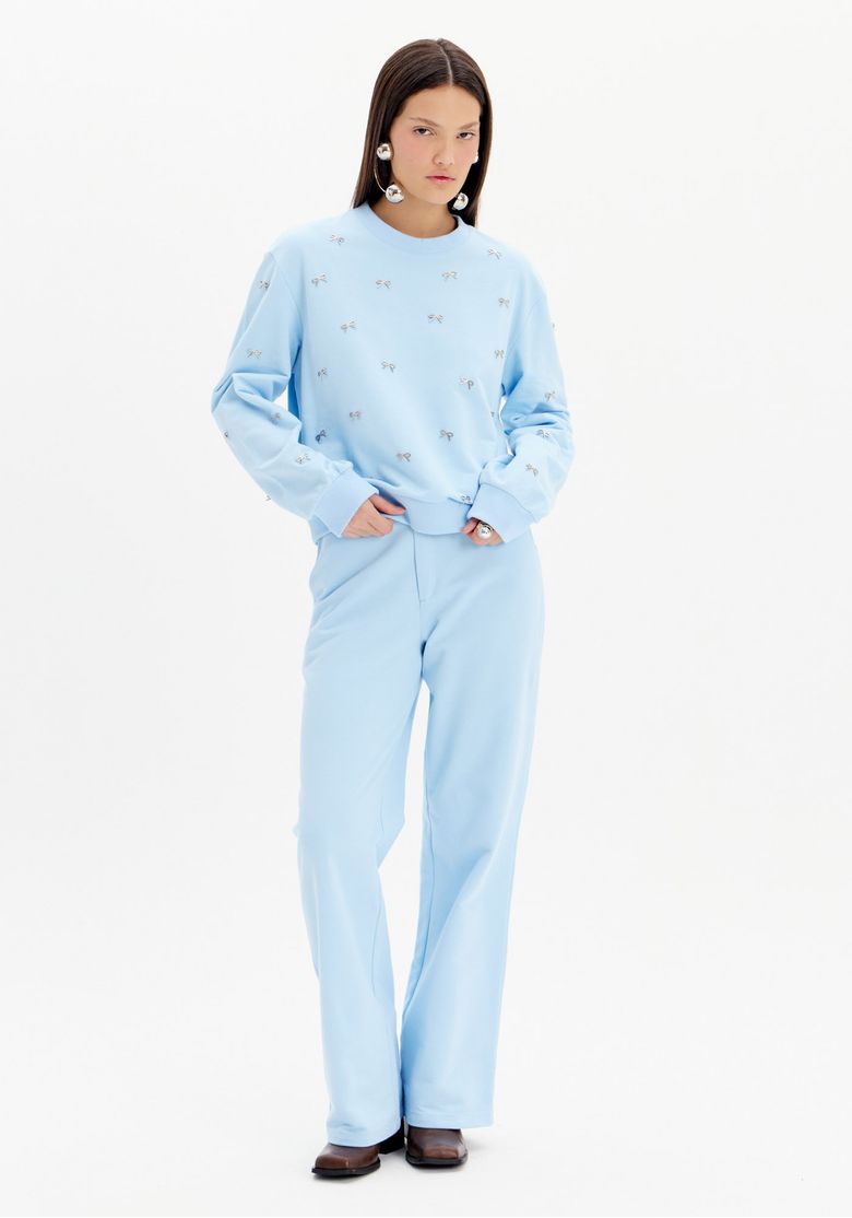 Modelo vestindo calça reta de moletom azul claro com blusa combinando, vista frontal.