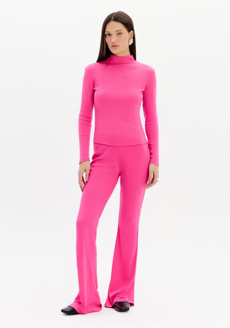 Modelo vestindo calça flare canelada rosa com top de manga longa combinando, vista frontal.