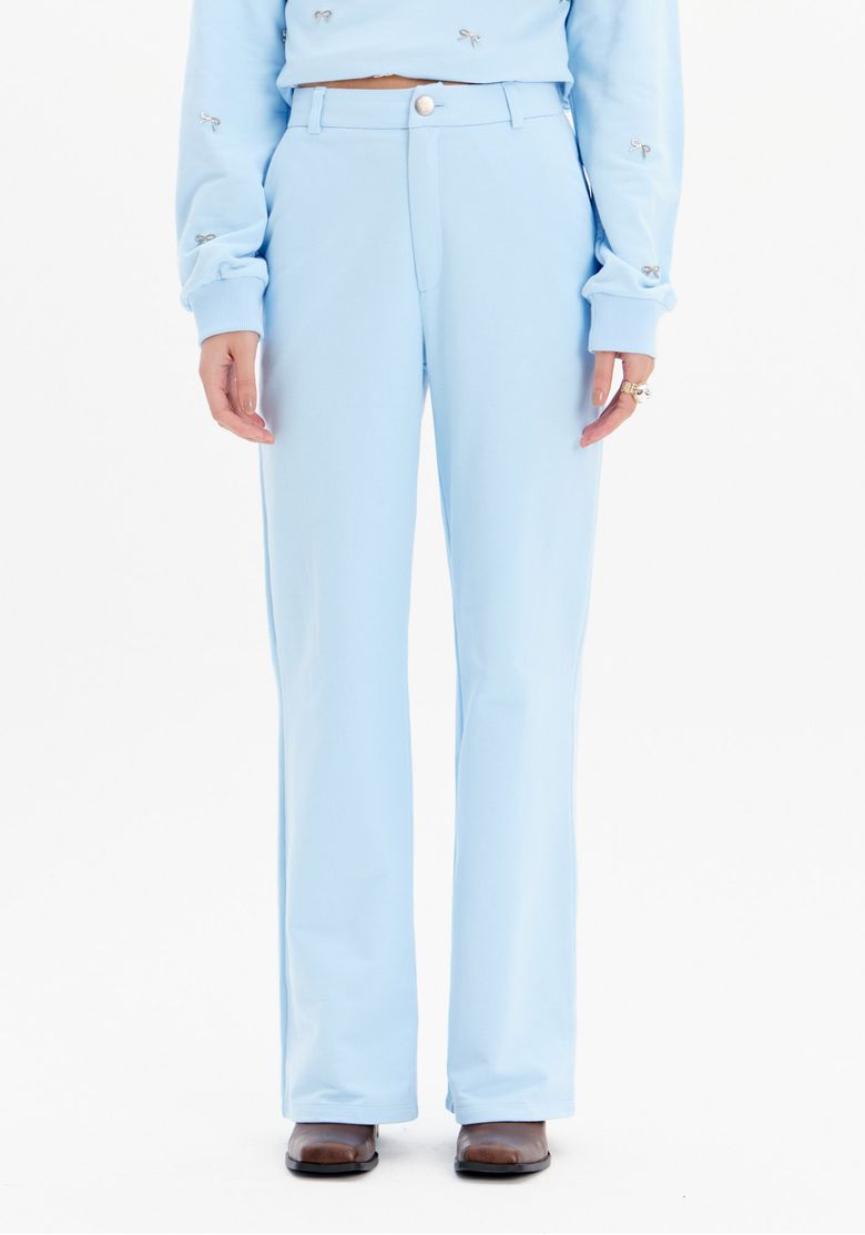 Detalhe da cintura alta e bolsos traseiros embutidos da calça reta de moletom azul claro.