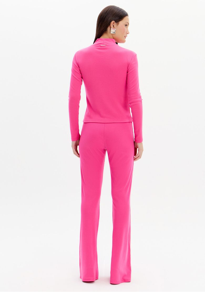 Modelo de costas vestindo conjunto rosa, com foco na calça flare canelada.