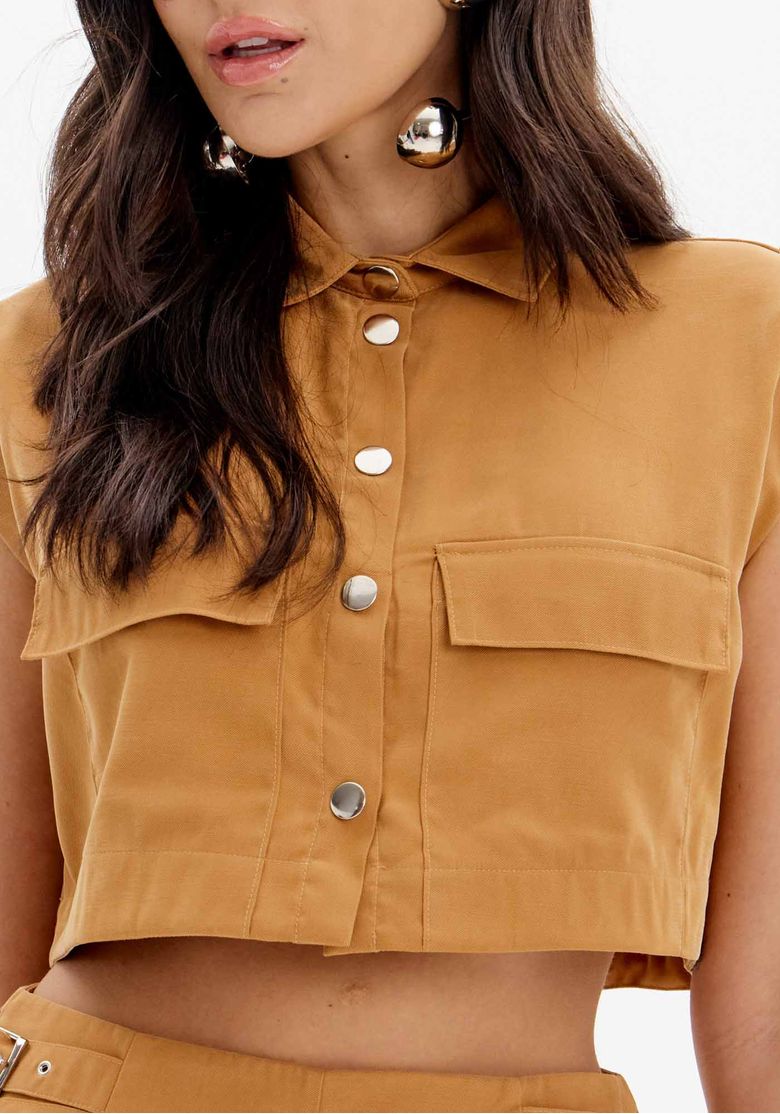 Detalhe do tecido e dos botões metálicos da camisa cropped.