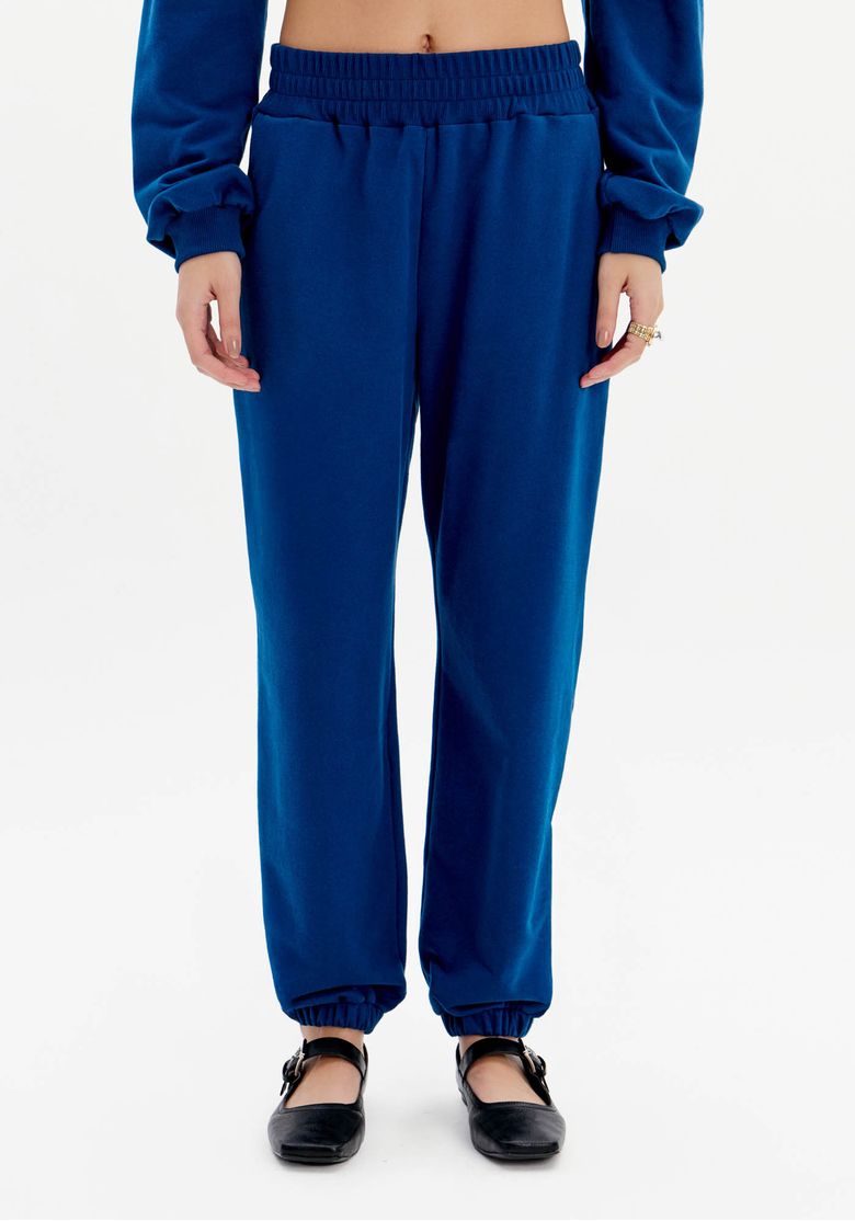 Close frontal da calça jogging de moletom azul com cintura alta, cós elástico e modelagem reta levemente afunilada