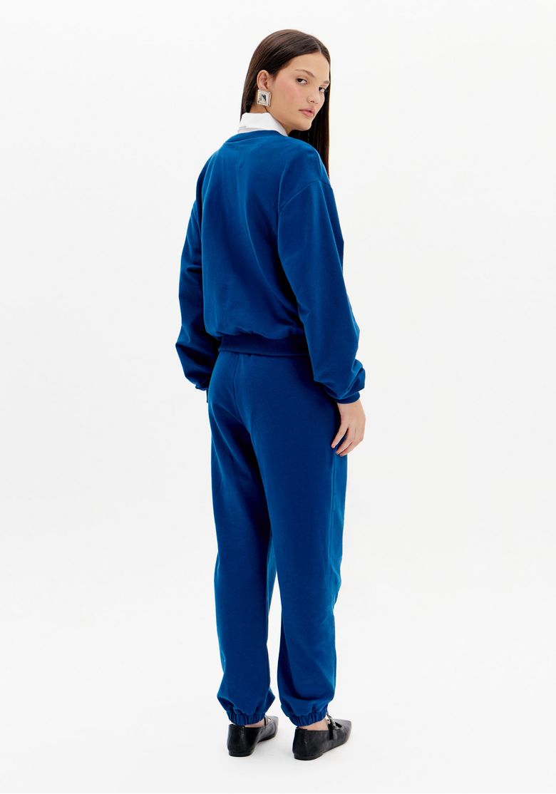 Vista traseira da calça jogging de moletom azul feminina com cintura alta, modelagem casual e barra ajustada
