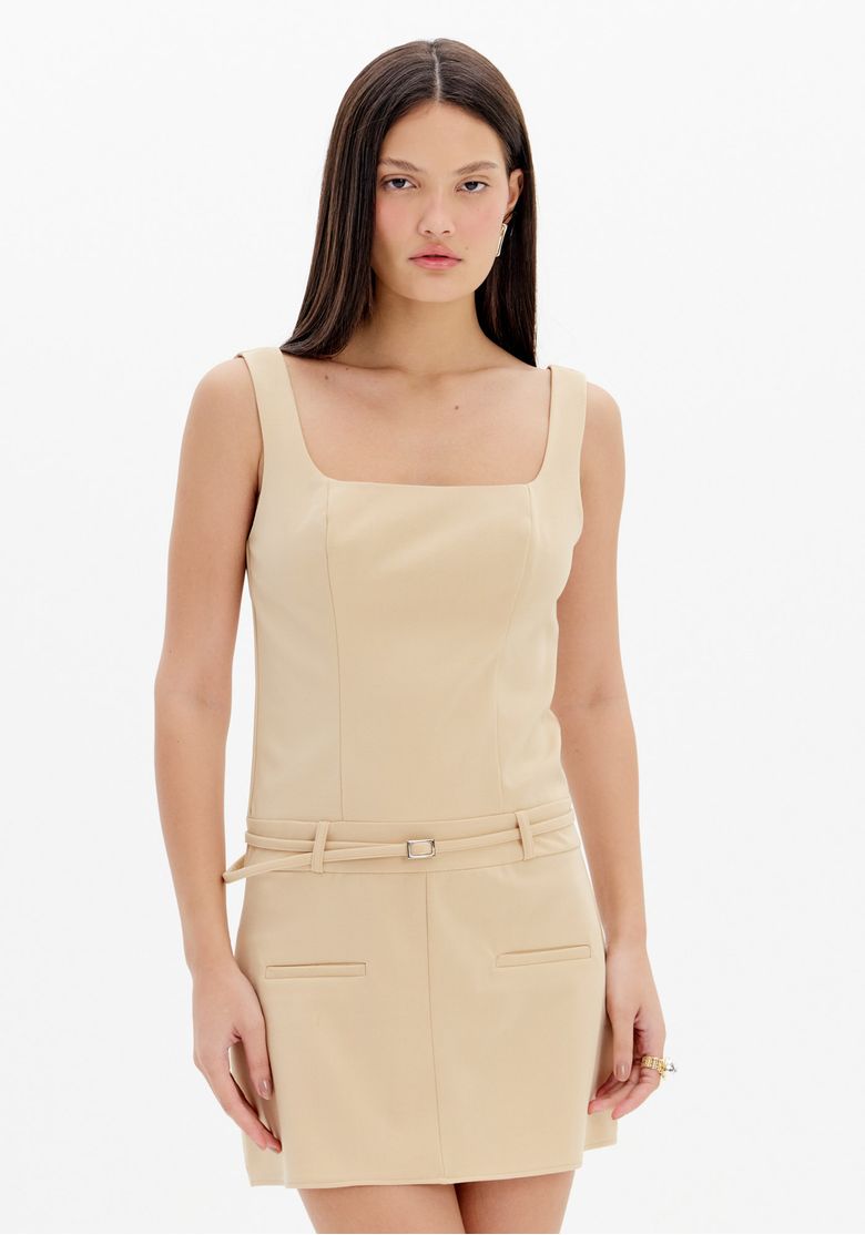 Close frontal de vestido curto bege feminino em alfaiataria com decote reto, alças largas, cinto delicado e detalhe de bolsos frontais
