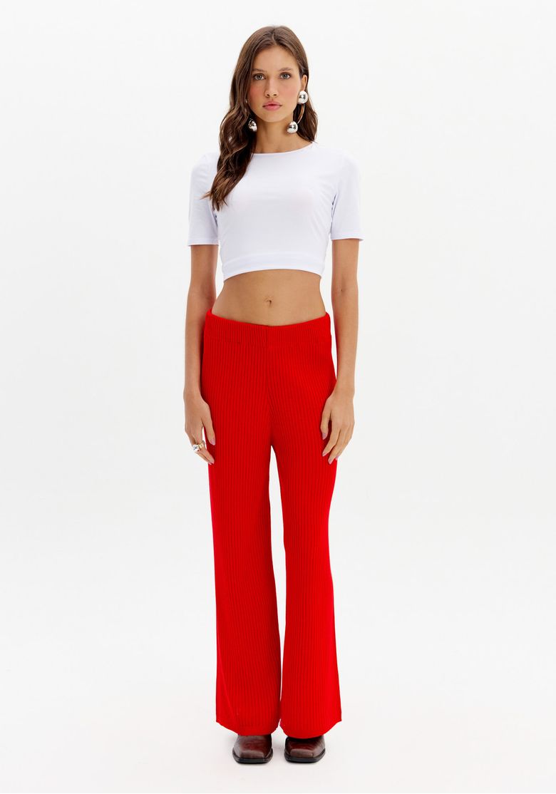 Modelo vestindo calça wide leg de tricô vermelha com top branco, vista frontal.