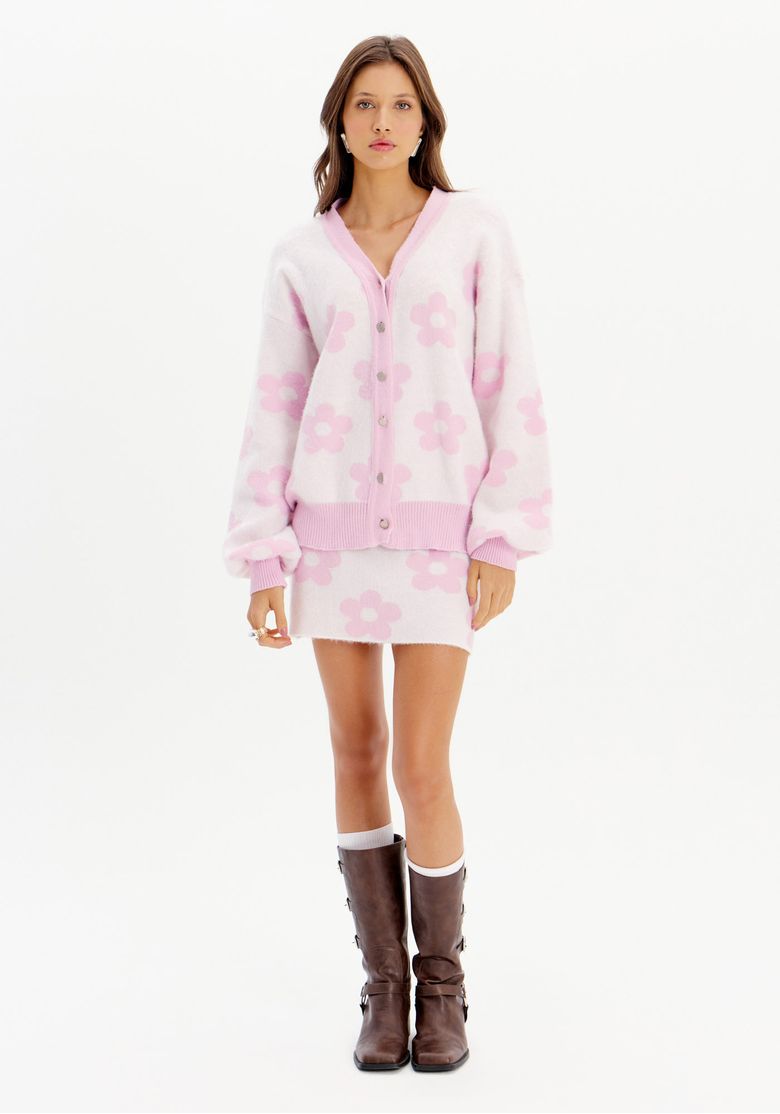 Modelo vestindo saia curta de tricô com estampa floral rosa e cardigan combinando.