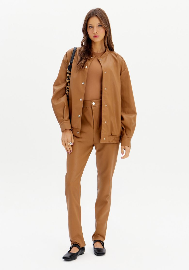 Modelo vestindo calça legging marrom com jaqueta combinando, em um look moderno.