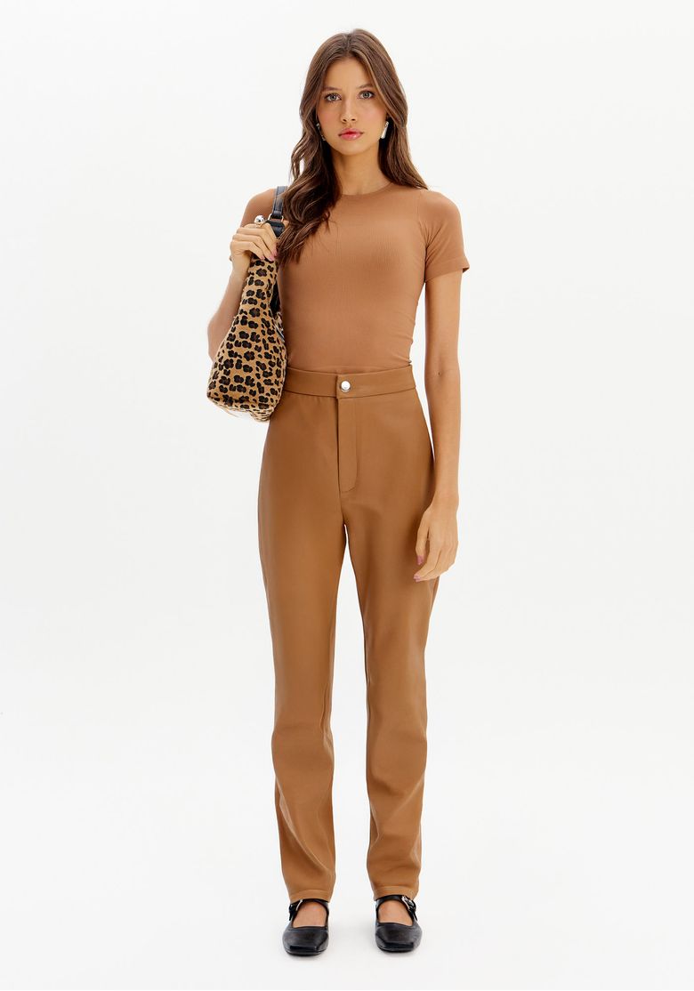 Modelo usando calça legging marrom com blusa ajustada, segurando uma bolsa estampada.