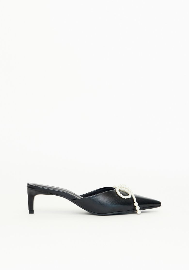 Scarpin mule preto com salto fino e laço de pérolas visto de lado.
