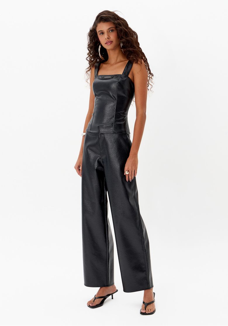 Vista lateral do look com blusa preta ajustada de PU texturizado e calça reta ampla
