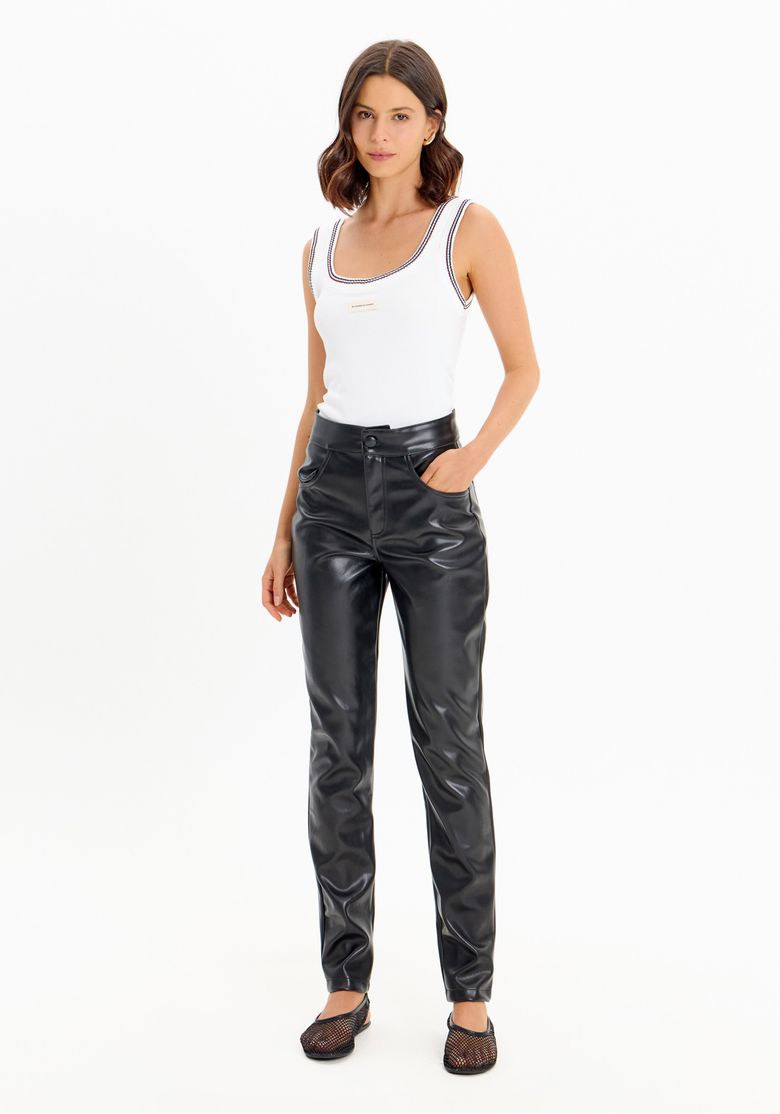 Mulher usando calça skinny preta de cintura alta em material sintético com bolsos frontais e body branco, vista frontal em look urbano