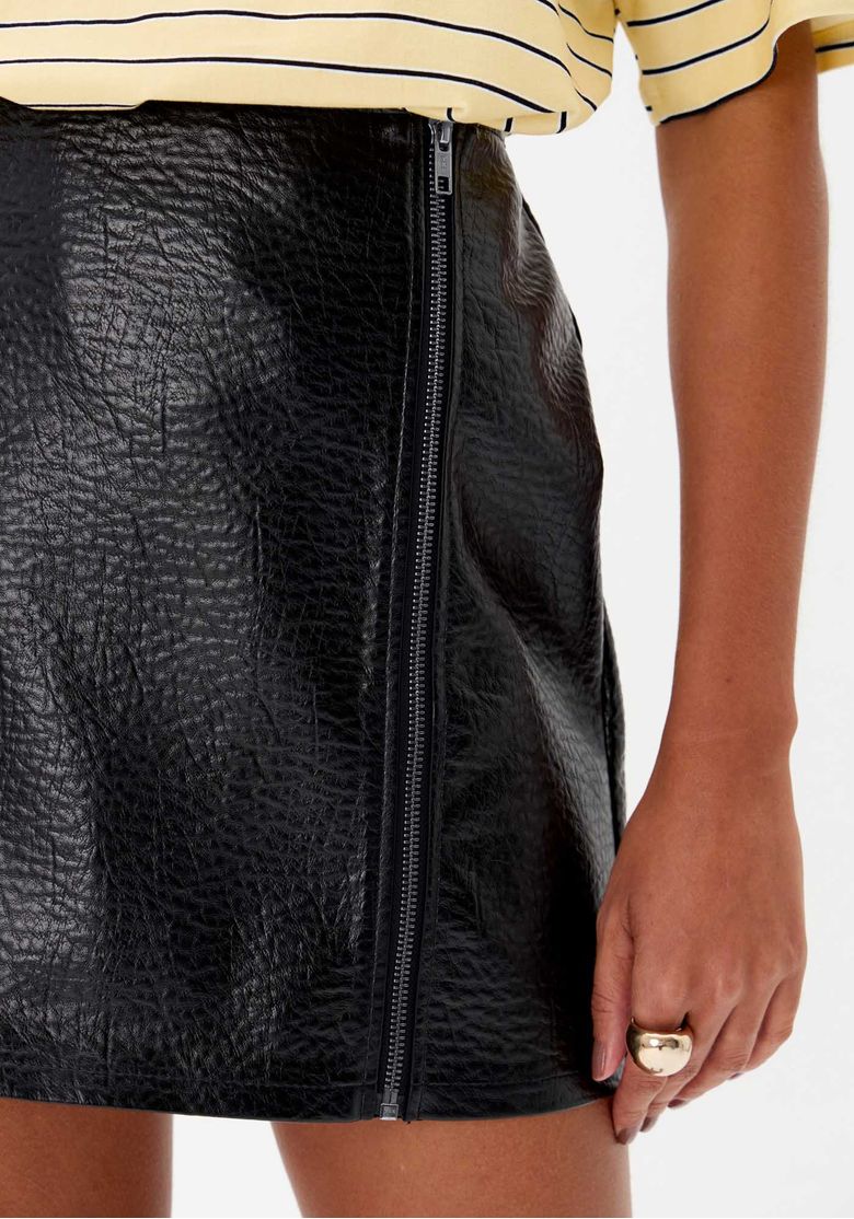 Vista traseira do look com saia curta preta reta em material sintético texturizado e blusa listrada