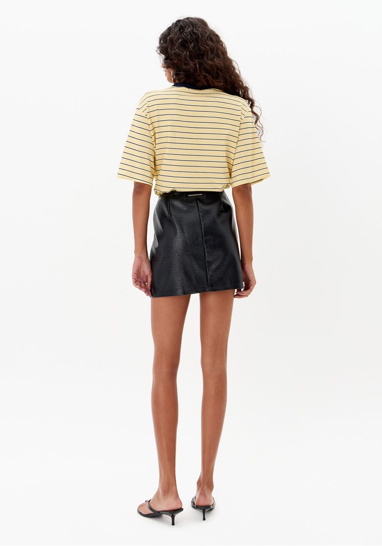 Look completo com saia curta preta de zíper frontal, blusa listrada ampla, bolsa preta e sandálias minimalistas