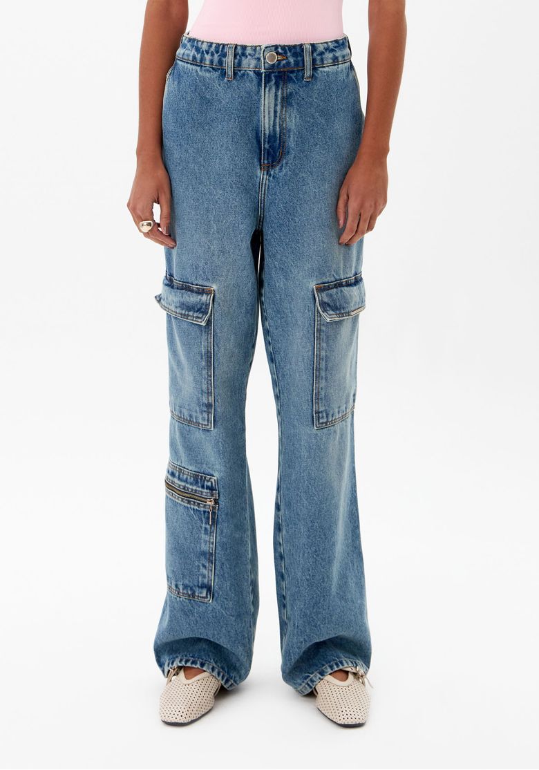 Detalhe frontal da calça jeans mostrando os bolsos funcionais e o cós com passantes.
