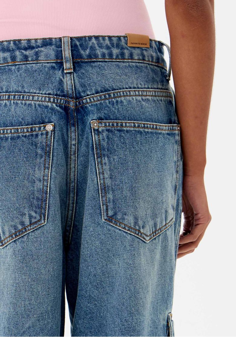 Close-up do cós da calça jeans com etiqueta de couro e detalhes da lavagem estonada.