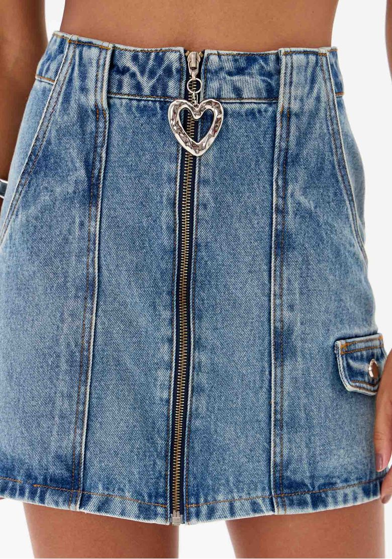 Detalhe do zíper frontal da saia jeans com puxador em formato de coração.