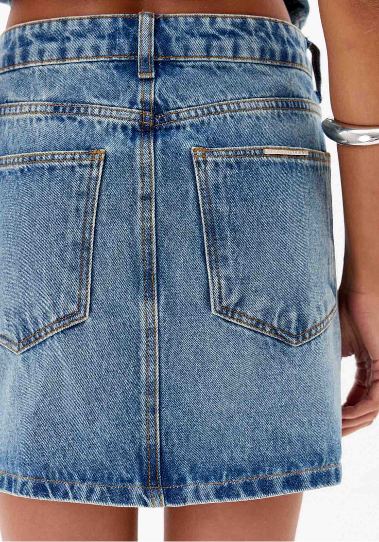 Close-up da parte traseira da saia jeans mostrando os bolsos e costuras.