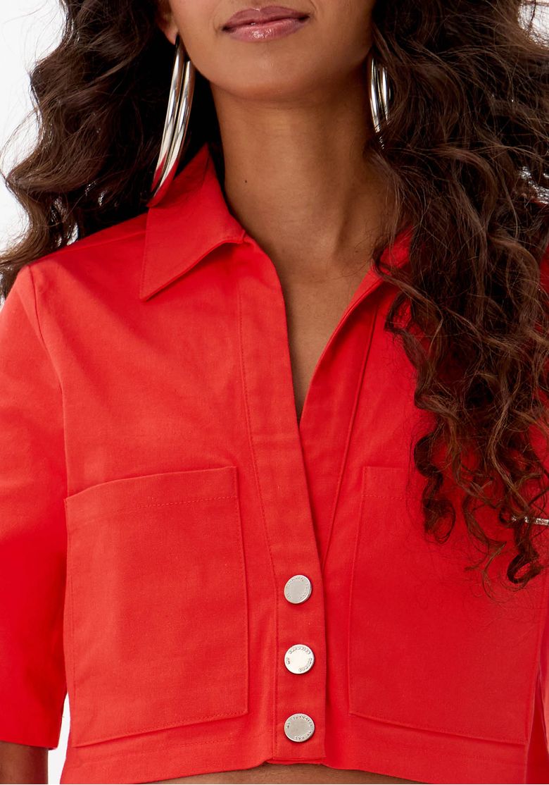 Detalhe do colarinho clássico e botões metálicos da camisa cropped.